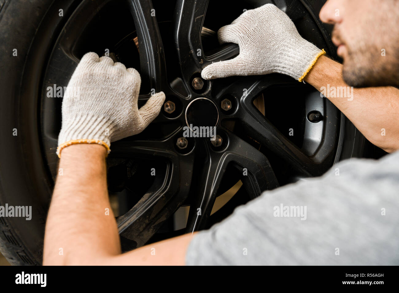 Vista parcial de la mecánica automotriz en uniforme usando guantes  protectores al taller de reparación de automóviles Fotografía de stock -  Alamy