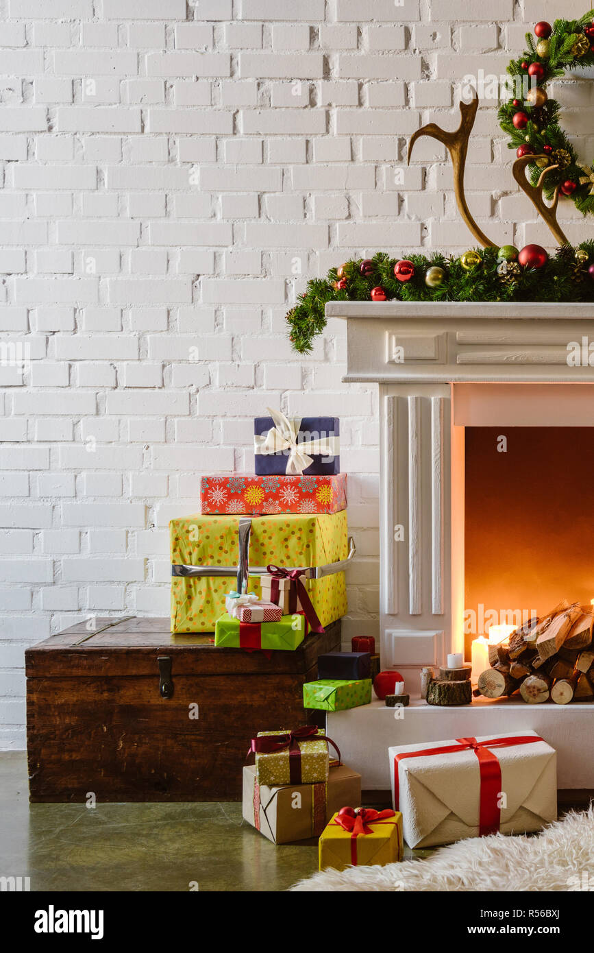 Adornos de Navidad con cajas de regalos cerca de la cálida chimenea en el salón Foto de stock