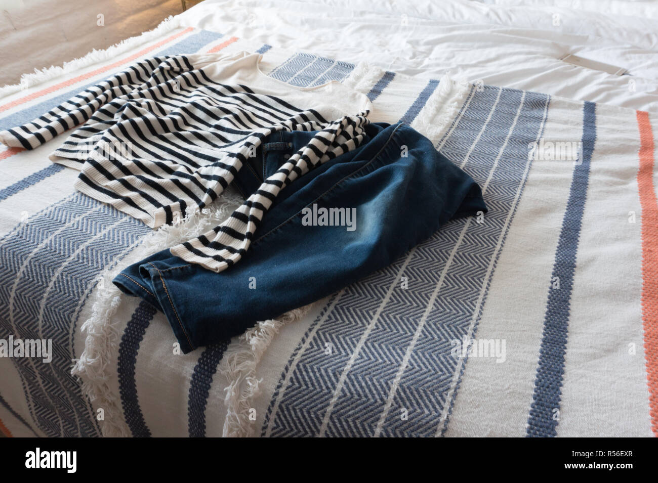 La ropa de una mujer dispuestos sobre una hermosa cama para prepararse para  el día -- una rayas marinero cachemir suéter y pantalones de mezclilla. La  aventura. Casual Fotografía de stock - Alamy