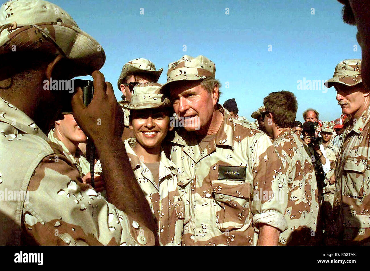 1993 - Medio de cerca del Presidente americano Bush teniendo tomé para posar para una foto con una mujer no identificada de los miembros de las fuerzas de los EE.UU. asignados a la misión en Somalia. Un gran número de otros miembros de la fuerza se han reunido en torno al Presidente. El Presidente visitó Somalia es mostrar gratitud a aquellos que participan en la misión de la operación Restaurar la esperanza. Foto de stock