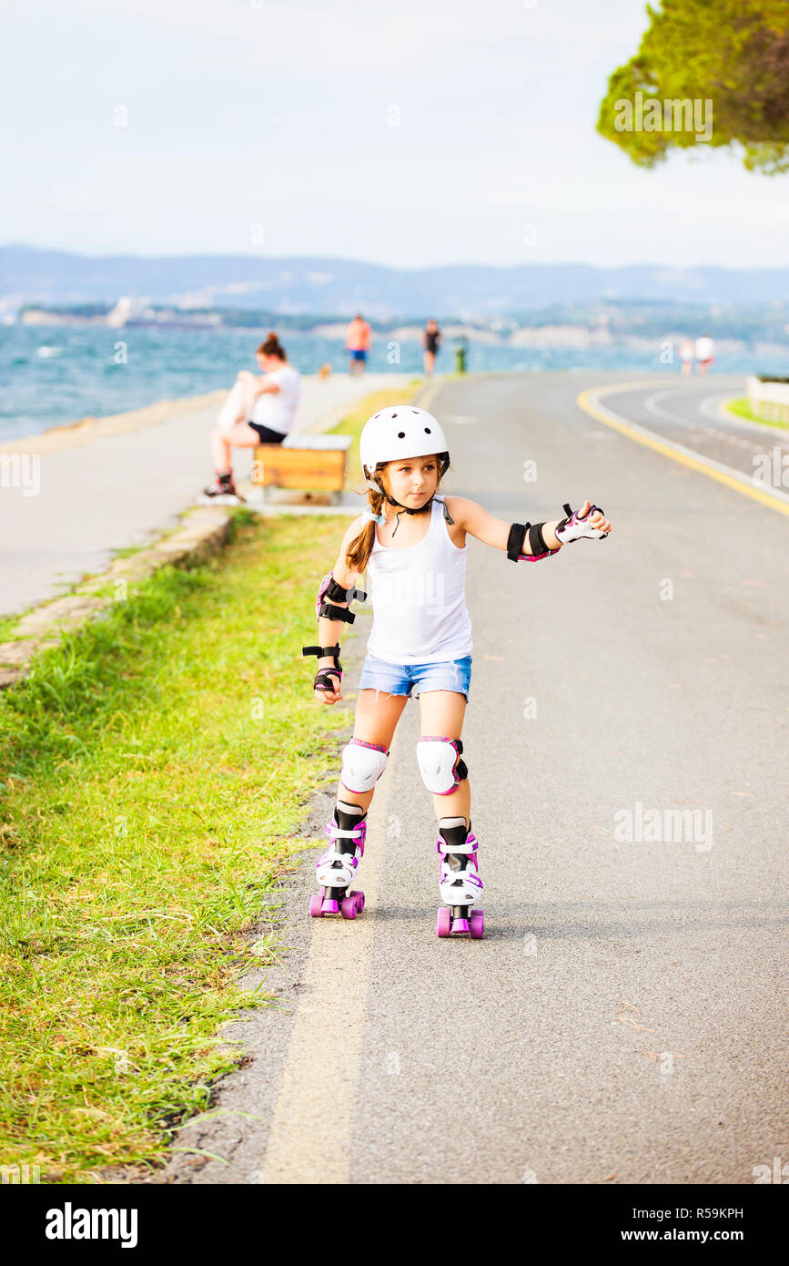 Una pequeña niña caucásica rodillo principiante en el litoral. Patinar y concepto de actividad al aire libre Foto de stock
