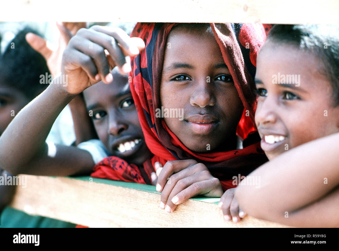 1993 - Los niños somalíes ver miembros del Batallón móvil de Construcción Naval 1 (NMCB-1) mientras trabajan para mejorar una escuela local durante el esfuerzo de socorro multinacional operación RESTAURAR LA ESPERANZA. Foto de stock