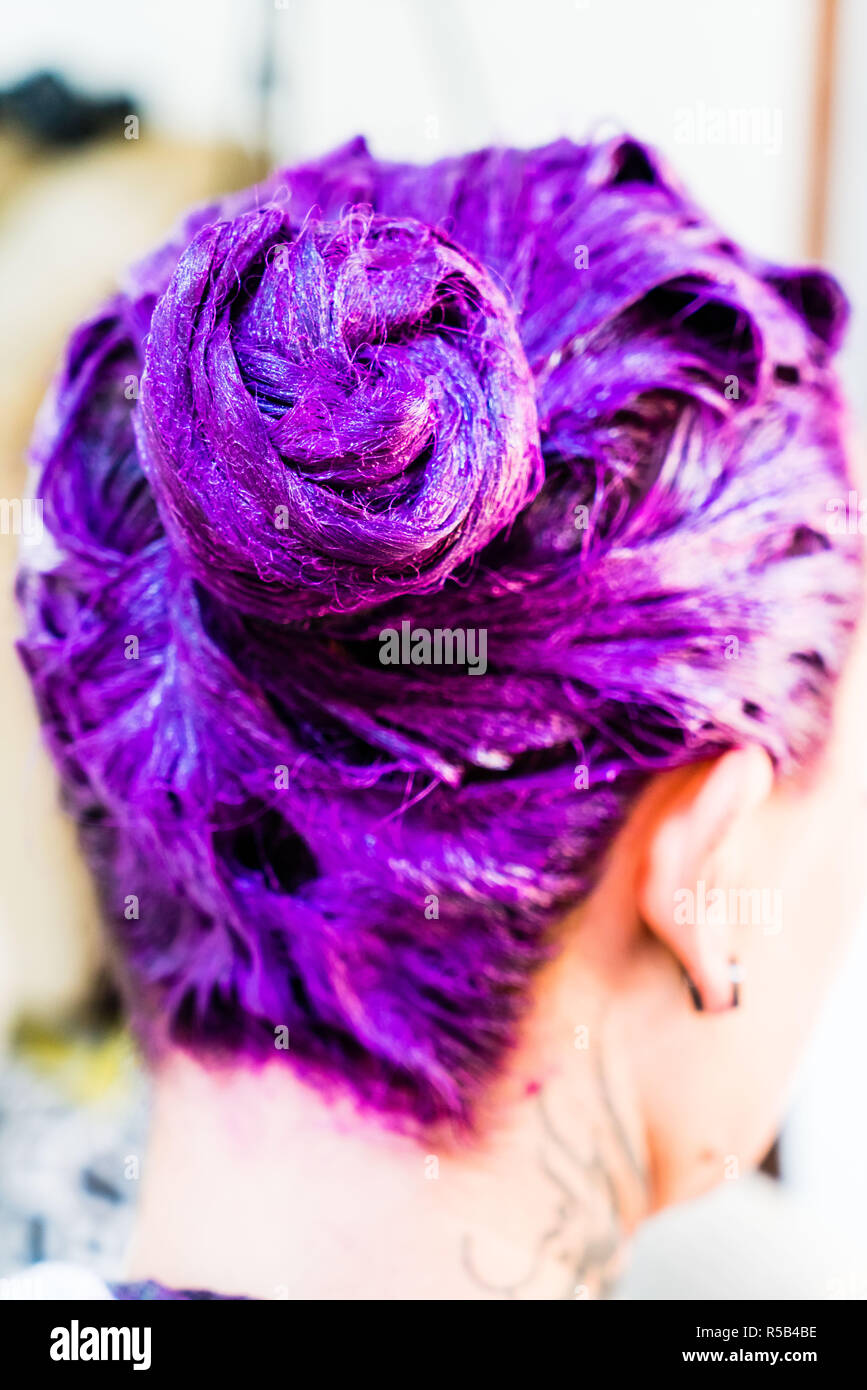 Mujer aplicando un champú de cabello púrpura. Foto de stock