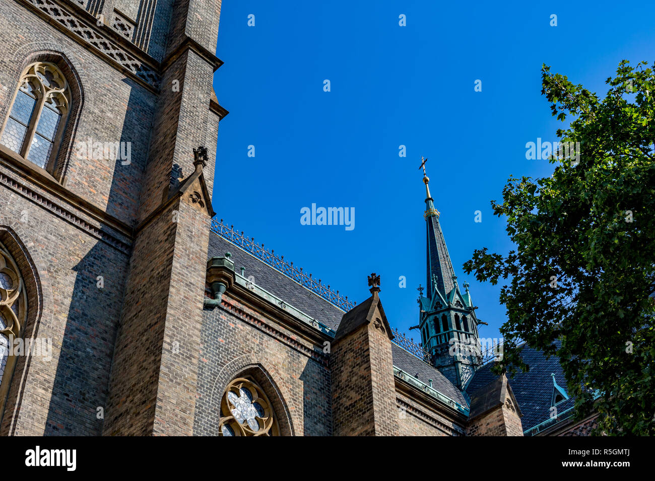 Vista parcial de la Catedral Católica en Praga, capital de la República Checa con la Tall sharp campanario gótico con la cruz en un cielo azul claro día de verano Foto de stock
