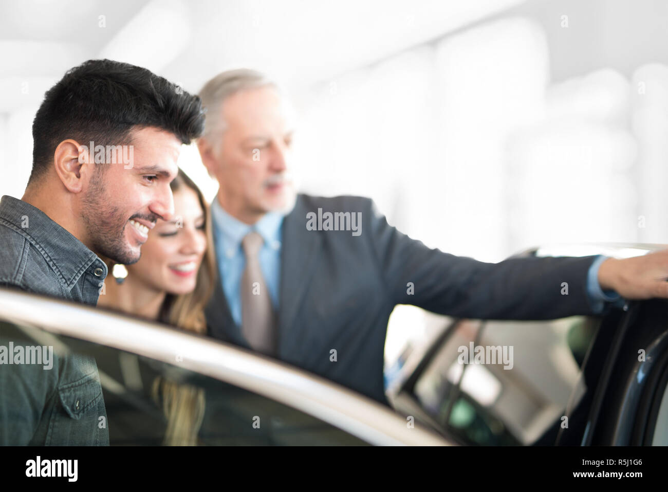 Feliz Familia Joven Hablando Con El Vendedor Y Eligiendo Su Nuevo Coche En Un Showroom 