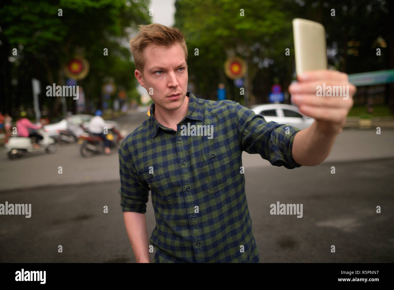 Joven apuesto hombre turístico teniendo selfie con teléfono móvil en Saigón Foto de stock