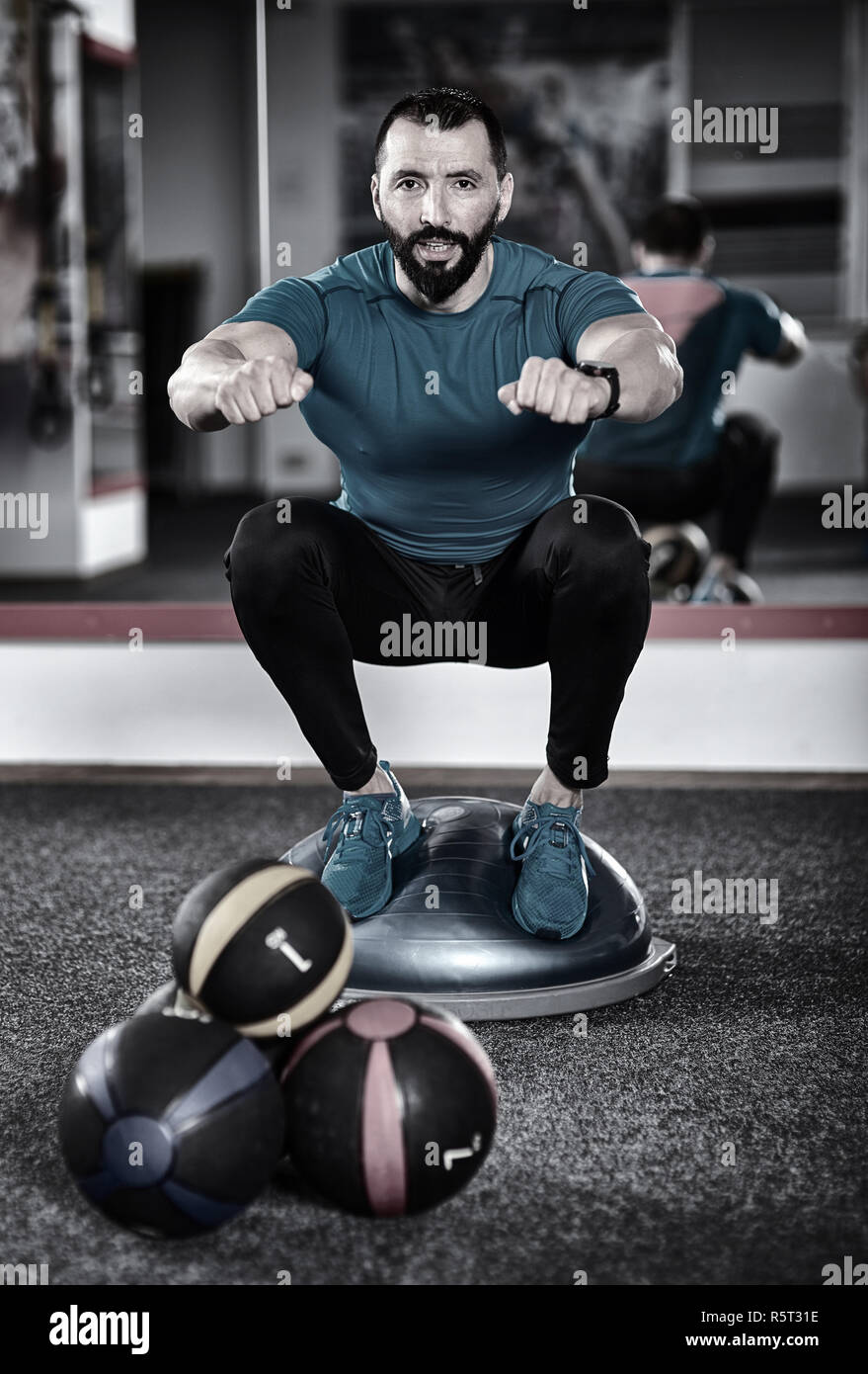 Trainer trabaja con una bola de equilibrio (bosu) en el gimnasio Fotografía  de stock - Alamy