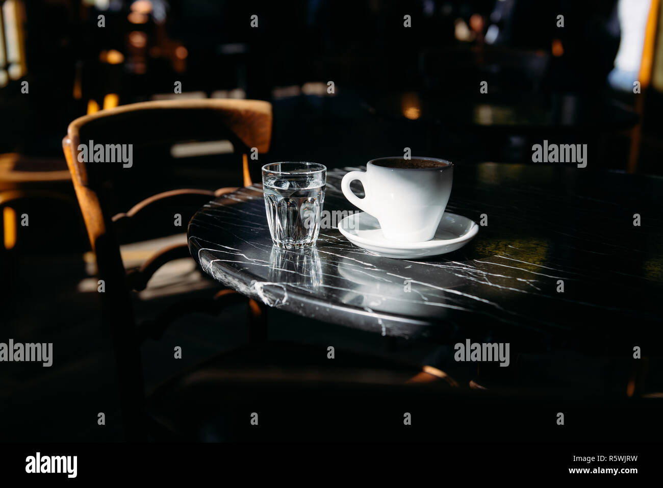 Close-up de una taza de café y un vaso de agua sobre una mesa Foto de stock