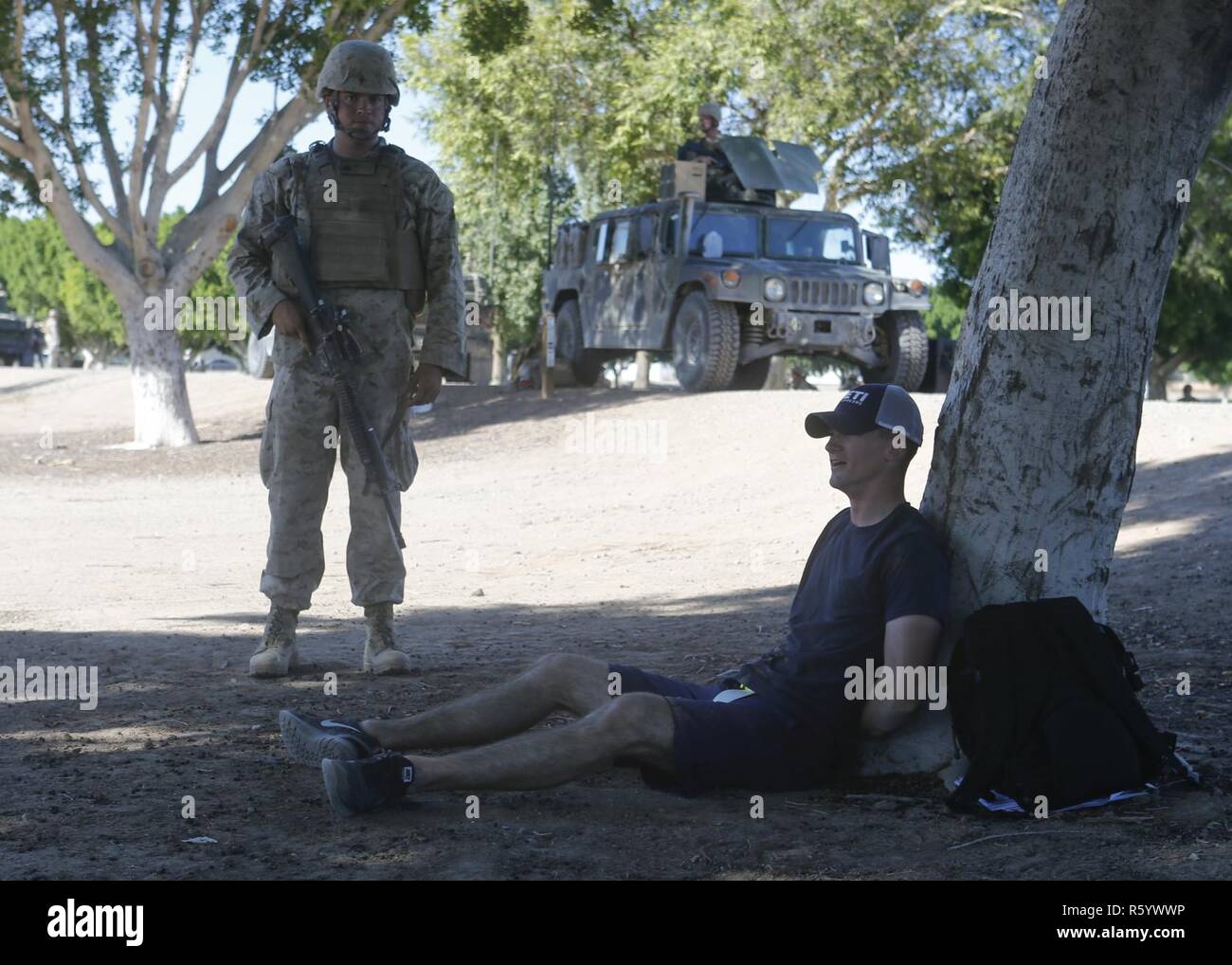 Un marine estadounidense con el Segundo Batallón, 6º Regimiento de la Infantería de Marina, la 2ª División de Infantería de Marina relojes detenidos un jugador de rol durante un asalto tres tácticas de soporte (AST-3) El ejercicio como parte del curso de Instructor de armas y tácticas (WTI) 2-17 en Kiwanis Park en Yuma, Arizona, 21 de abril de 2017. AST-3 es un ejercicio centrado en la realización de la operación de evacuación de no combatientes (NEO) en un entorno urbano, y proporcionando al mismo tiempo la asistencia humanitaria extranjera (FHA) para la simulación de la nación anfitriona. El WTI es un evento de capacitación de siete semanas, acogido por la Aviación Marina armas y tácticas de escuadrón MAWTS Uno (cuadro 1), lo cual hincapié Foto de stock