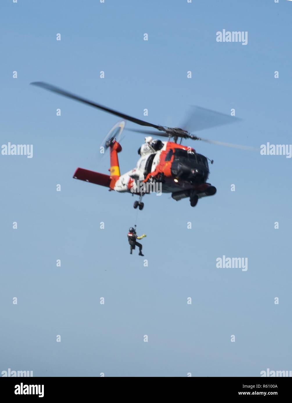Una tripulación de Air Station San Diego es subirla un miembro hasta un guardacostas Jayhawk MH60 helicóptero de rescate durante el acantilado la formación fuera del acantilado del punto Vicente Faro en Rancho Palos Verdes, California el 26 de abril de 2017. La formación contribuye consistentemente las tripulaciones estancia adepto de situaciones donde tendrán que realizar un acantilado de rescate. Foto de stock