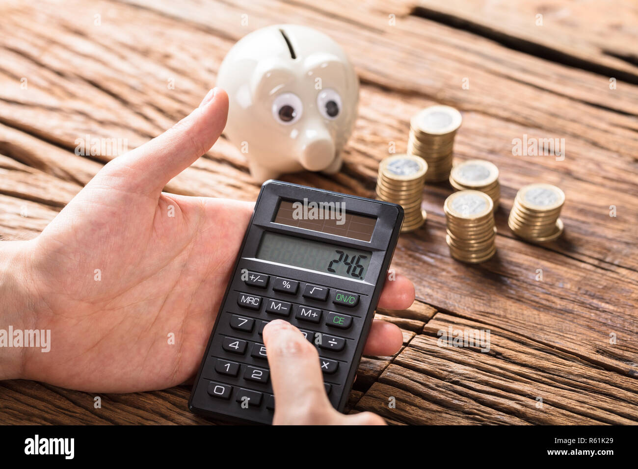 La persona que calcula en calculadora con monedas y Hucha Fotografía de  stock - Alamy