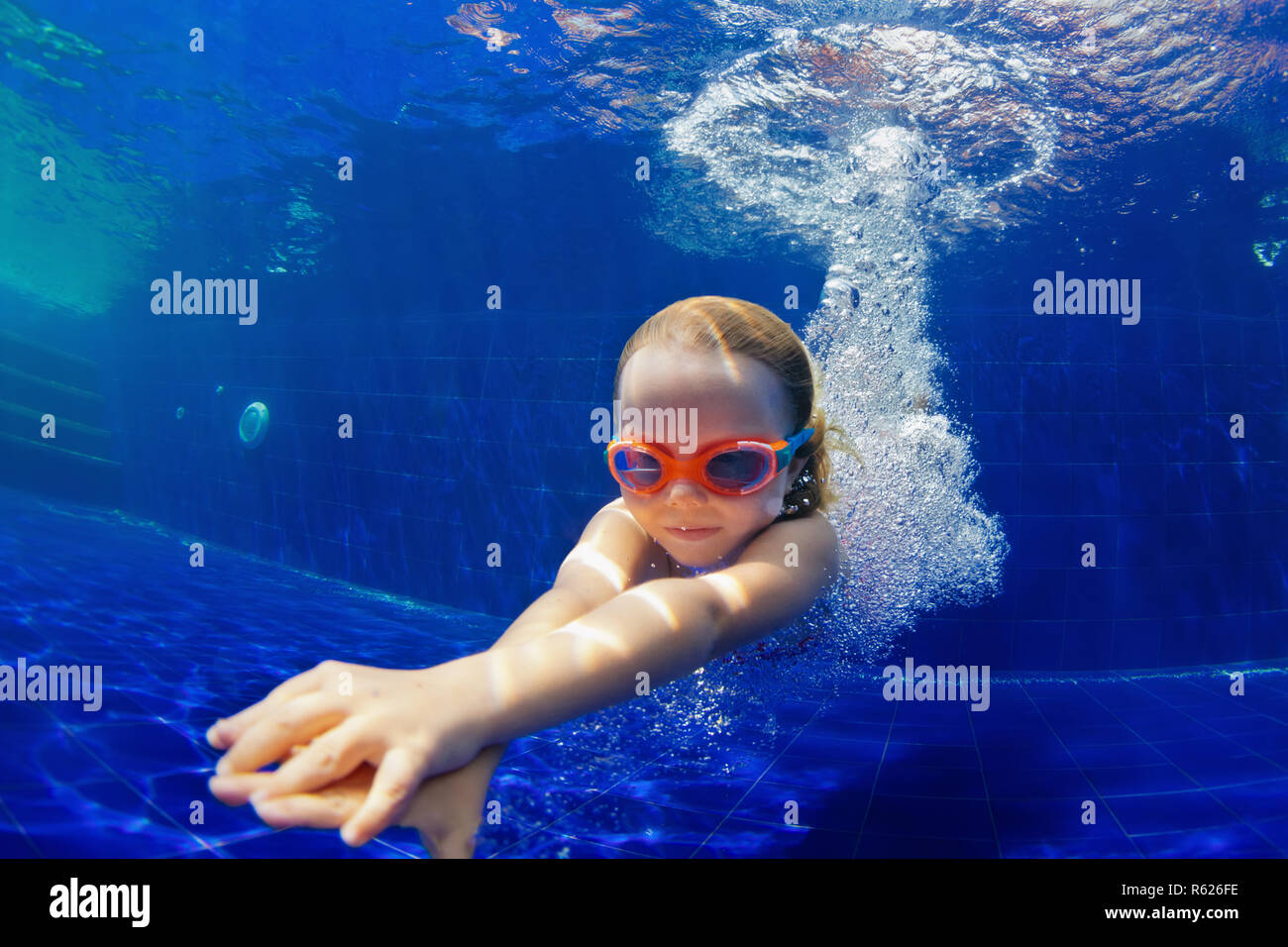 Familia feliz en la piscina. Niño sonriente en gafas de bucear, nadar en la piscina con la diversión - saltar profundidades submarinas. Estilo de vida saludable, la gente deporte acuático Foto de stock