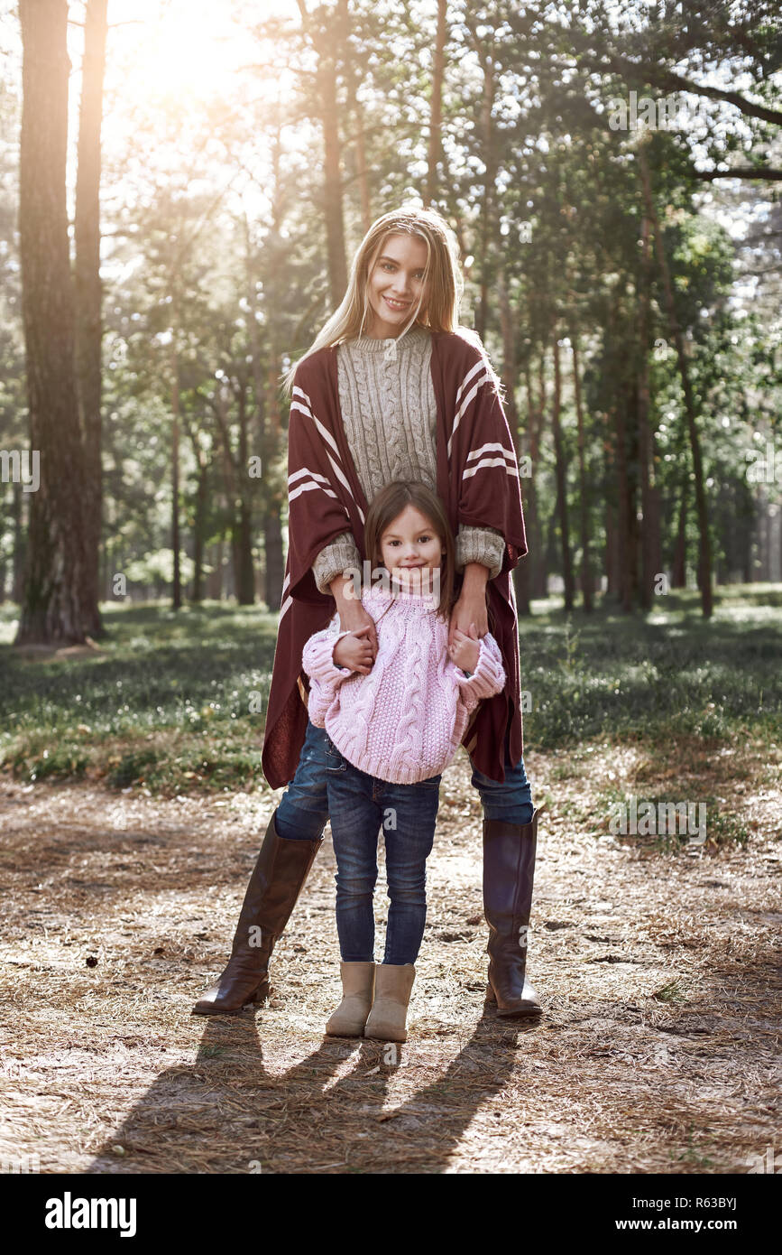 Niña y su madre en el parque de otoño. La mujer está vistiendo una túnica,  tejida elegante chica está en rosa brillante suéter Fotografía de stock -  Alamy