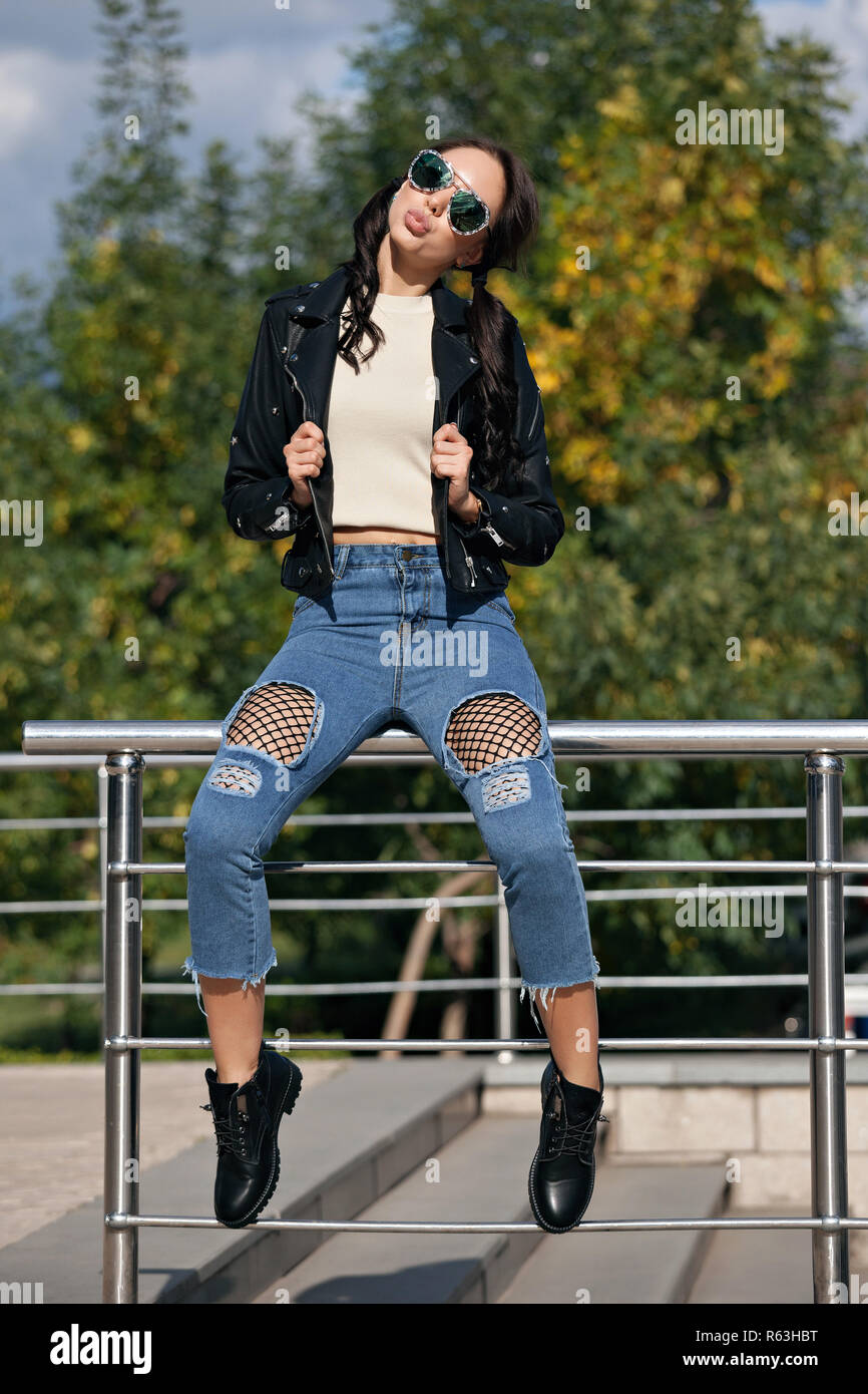 Moda joven en estilo de rock ropa, chaqueta de cuero negro, jeans panties  en una cuadrícula en jeans maltratadas Fotografía de stock - Alamy