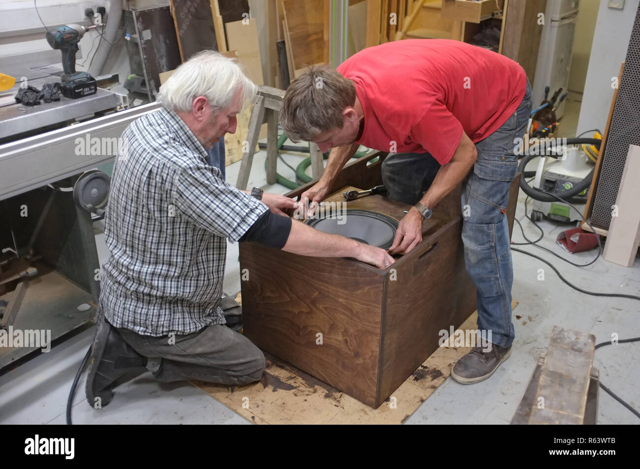 Dos carpinteros la construcción de un altavoz para un sistema de sonido. Aquí la inserción de un conductor. Foto de stock