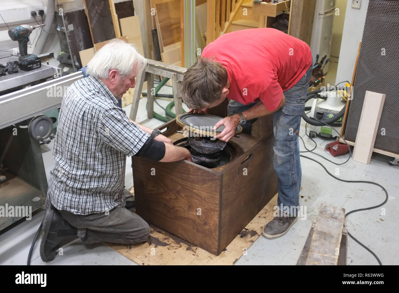 Dos carpinteros la construcción de un altavoz para un sistema de sonido. Aquí la inserción de un conductor. Foto de stock