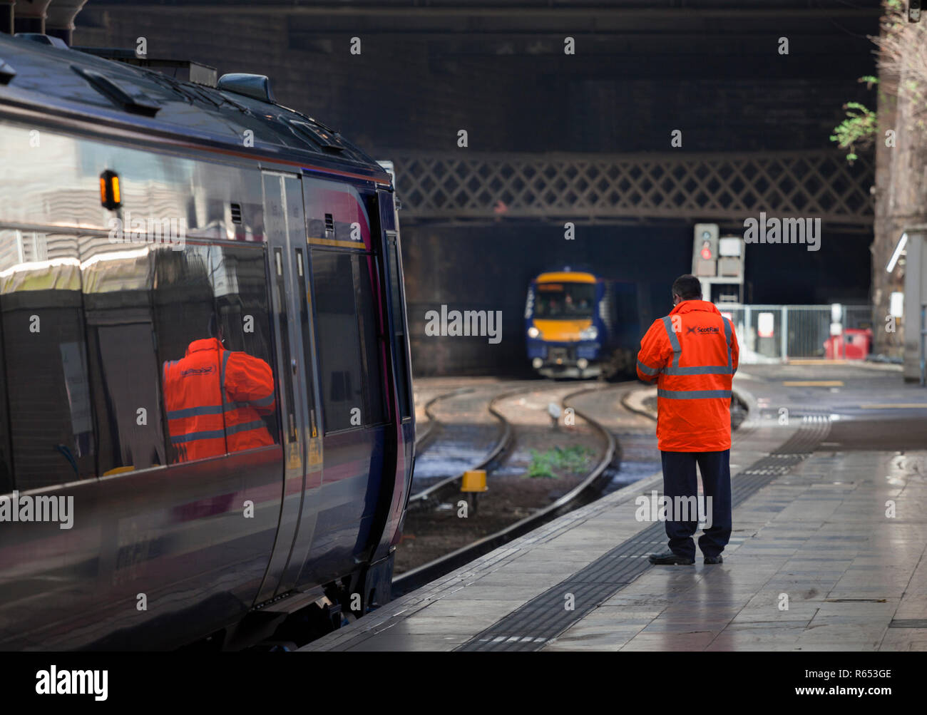 El conductor de un tren clase Scotrail 170 turbostar en Glasgow Queen Street, a punto de embarcar en el tren como otro llega a la estación. Foto de stock