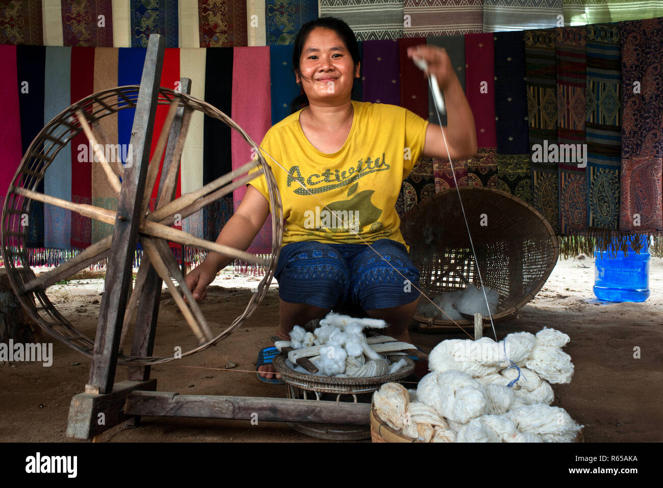 Mujer local utiliza técnicas tradicionales para spin lana de madera en un Spinning Wheels una aldea en Laos Foto de stock