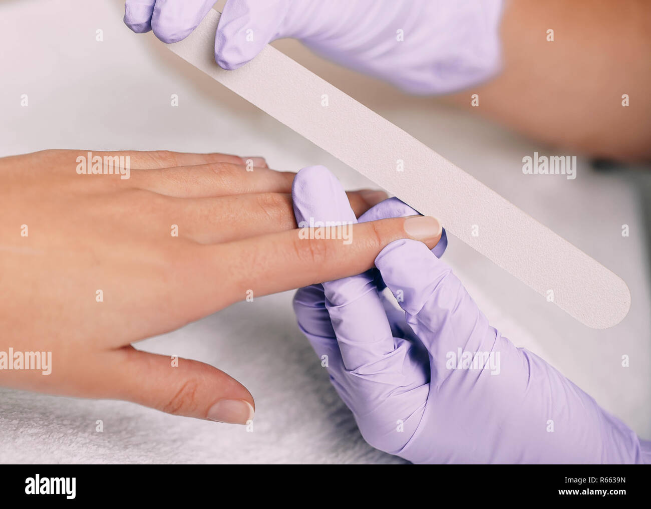 Mujer contraer una higiene manicura con lima de uñas en el salón de uñas Foto de stock