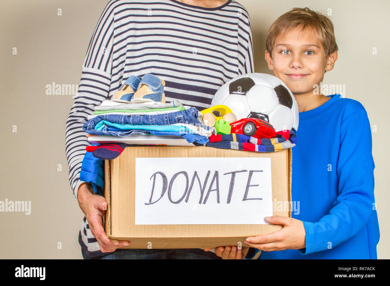 Concepto de donación. Donar caja con ropa, libros y juguetes en el niño y  la madre mano Fotografía de stock - Alamy