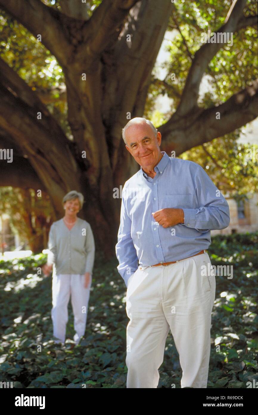 Retrato, Ganzfigur, infierno gekleidetes Im Sommer lachend Seniorenpaar steht unter einem Baum Foto de stock