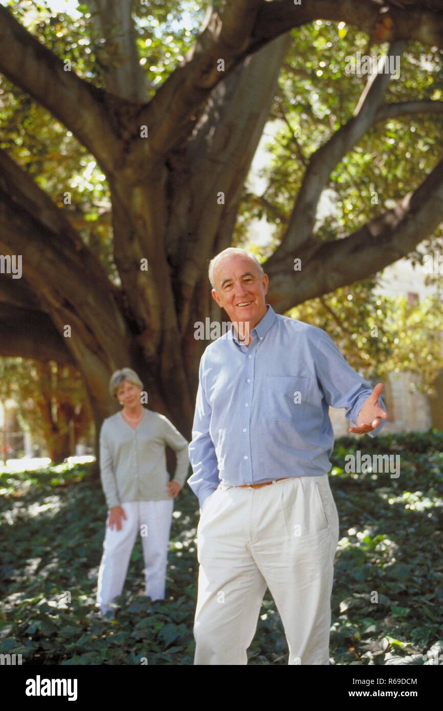 Retrato, Ganzfigur, infierno gekleidetes Seniorenpaar steht Im Sommer unter einem Baum Foto de stock