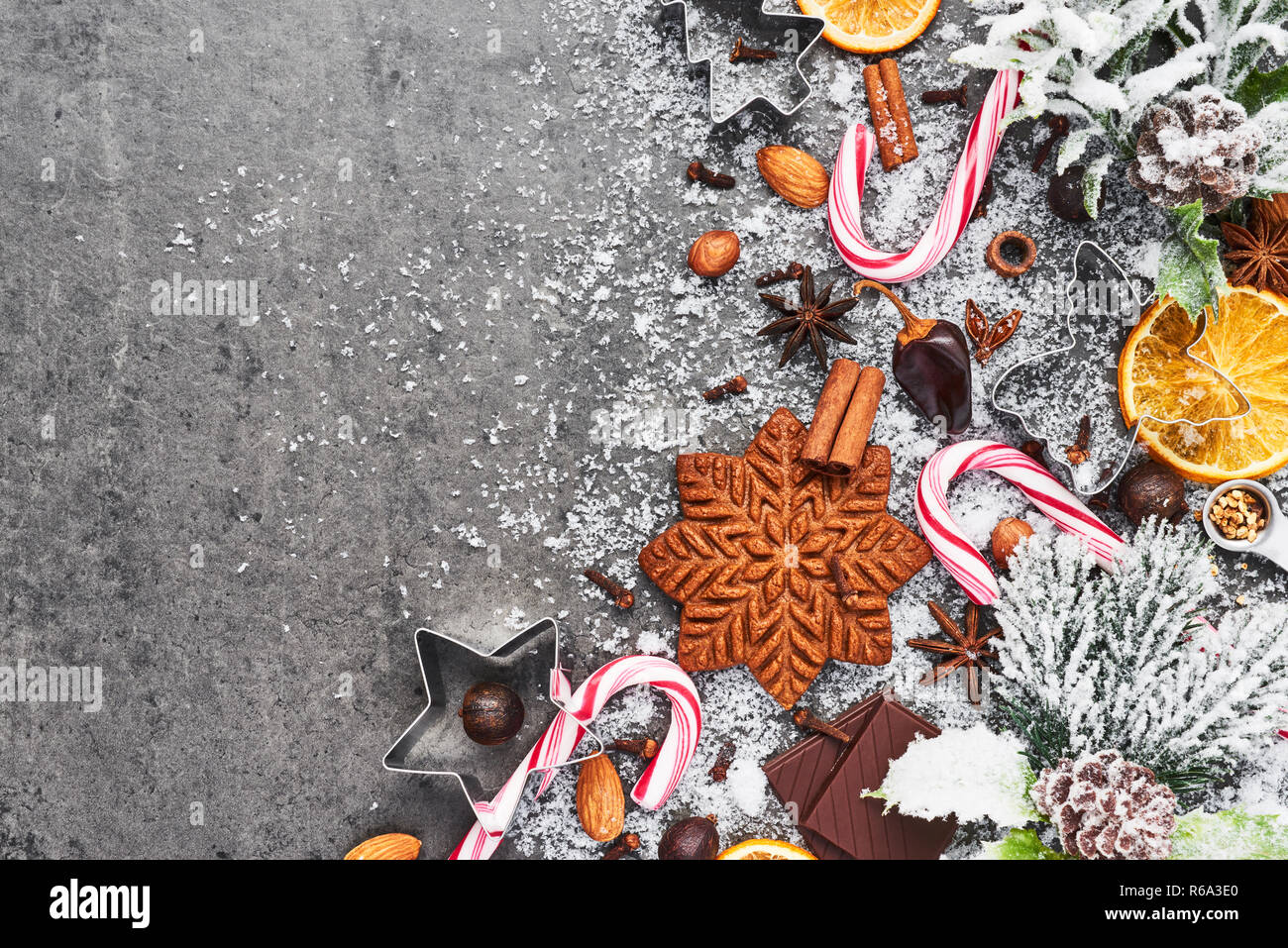 Fondo de cocción de vacaciones. Hornear las galletas de jengibre de Navidad con cortadores y especias en tabla de cemento gris con nieve. Hornear o cocinar en vacaciones Foto de stock