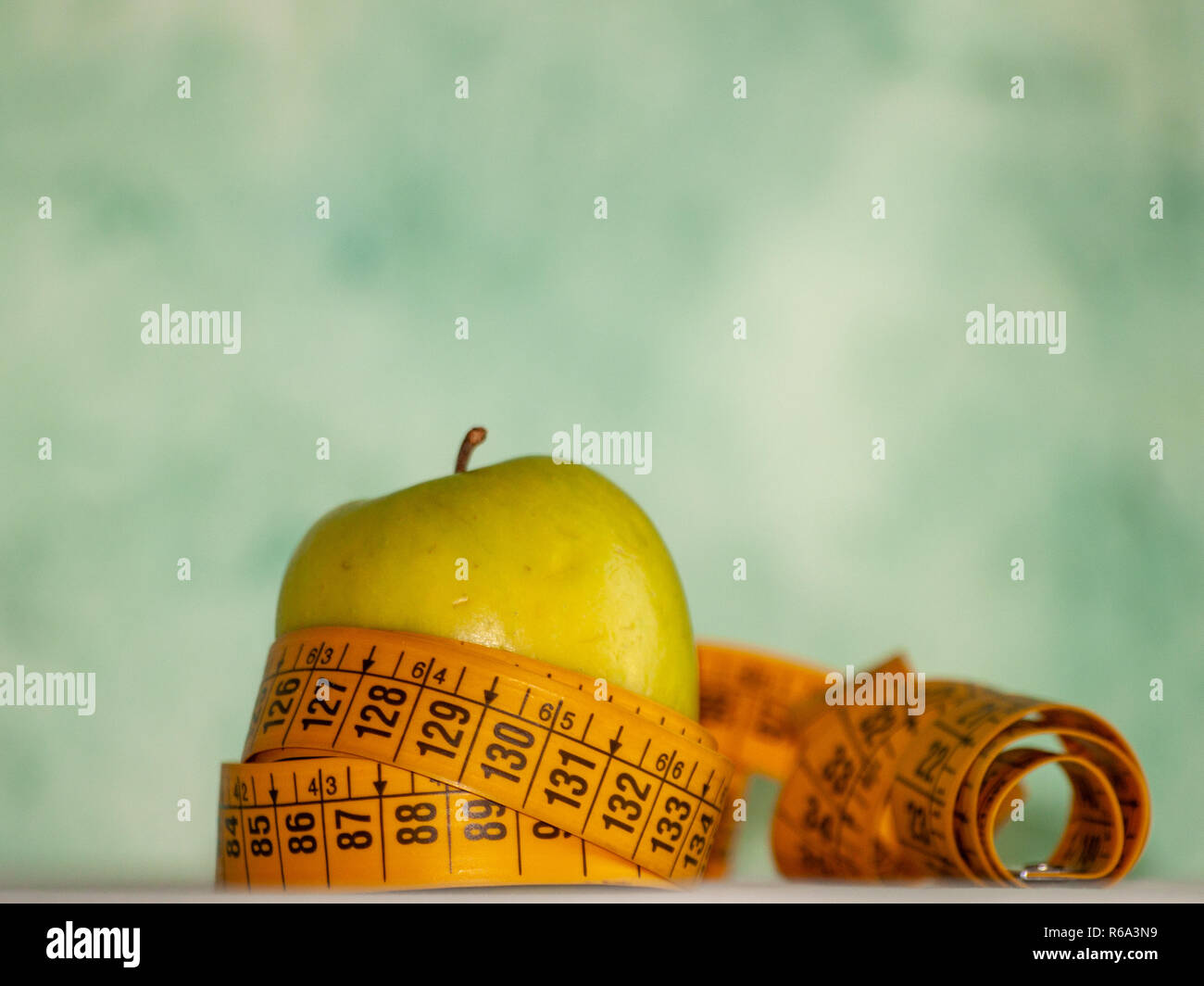 Concepto de obesidad. Una manzana verde y una cinta métrica en la parte superior de una tabla Foto de stock