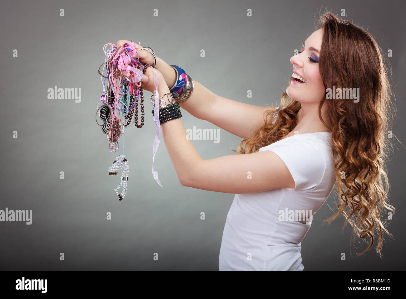 Guapa joven mujer vistiendo pulseras y anillos celebrar muchas abundante de  joyas collares cordones. Retrato de hermosa niña moda en studio Fotografía  de stock - Alamy