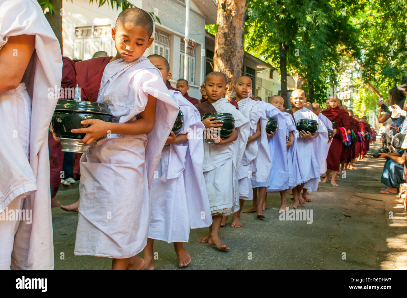 Novicios budistas caminar para recoger limosnas y ofrendas en Amarapura, cerca de Mandalay, Myanmar esta procesión se celebra cada día Foto de stock