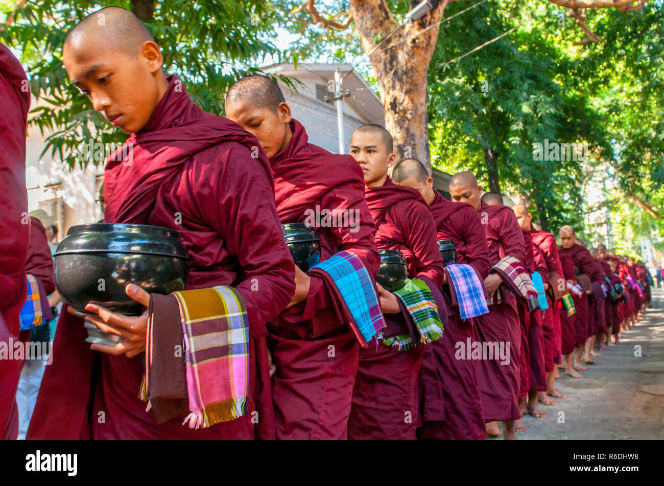 Novicios budistas caminar para recoger limosnas y ofrendas en Amarapura, cerca de Mandalay, Myanmar esta procesión se celebra cada día Foto de stock