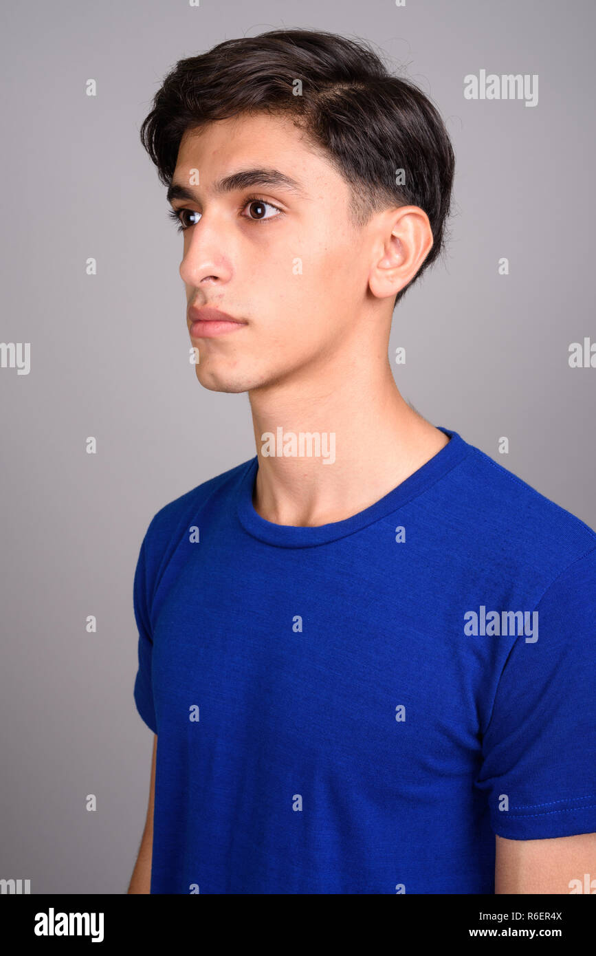 Joven apuesto adolescente persa contra el fondo gris Foto de stock