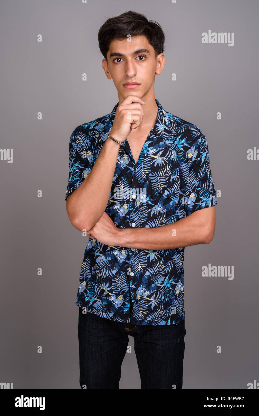 Joven apuesto adolescente persa vistiendo la camiseta hawaiana contra Foto de stock