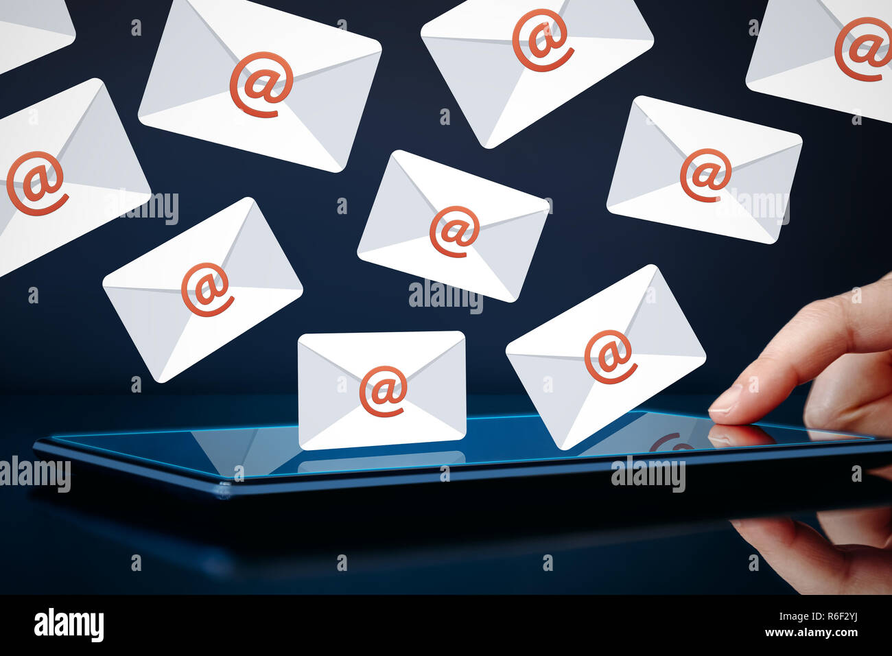 Newsletter y email marketing concepto. Tocar mano tablet mostrando iconos de correo electrónico sobre un fondo oscuro. Foto de stock