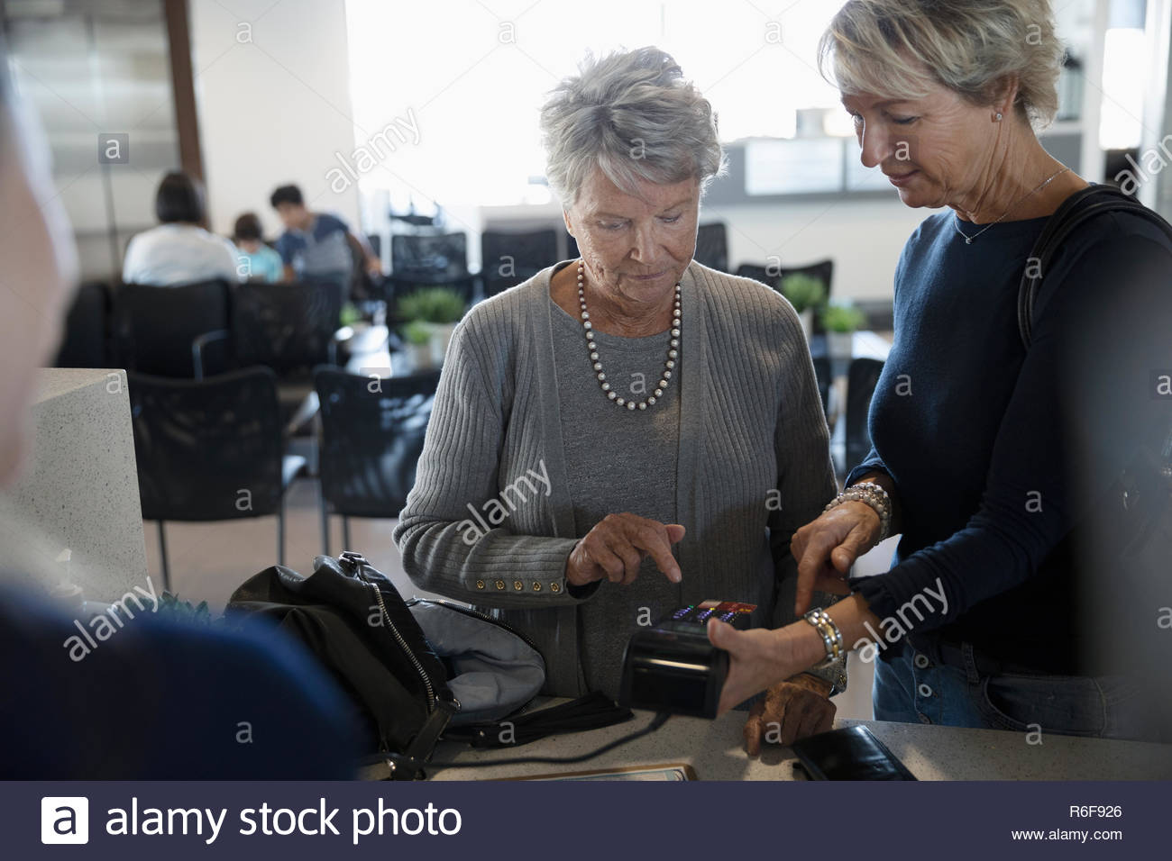 Mujer ayudando a pagar a la madre senior clinic check-in Foto de stock