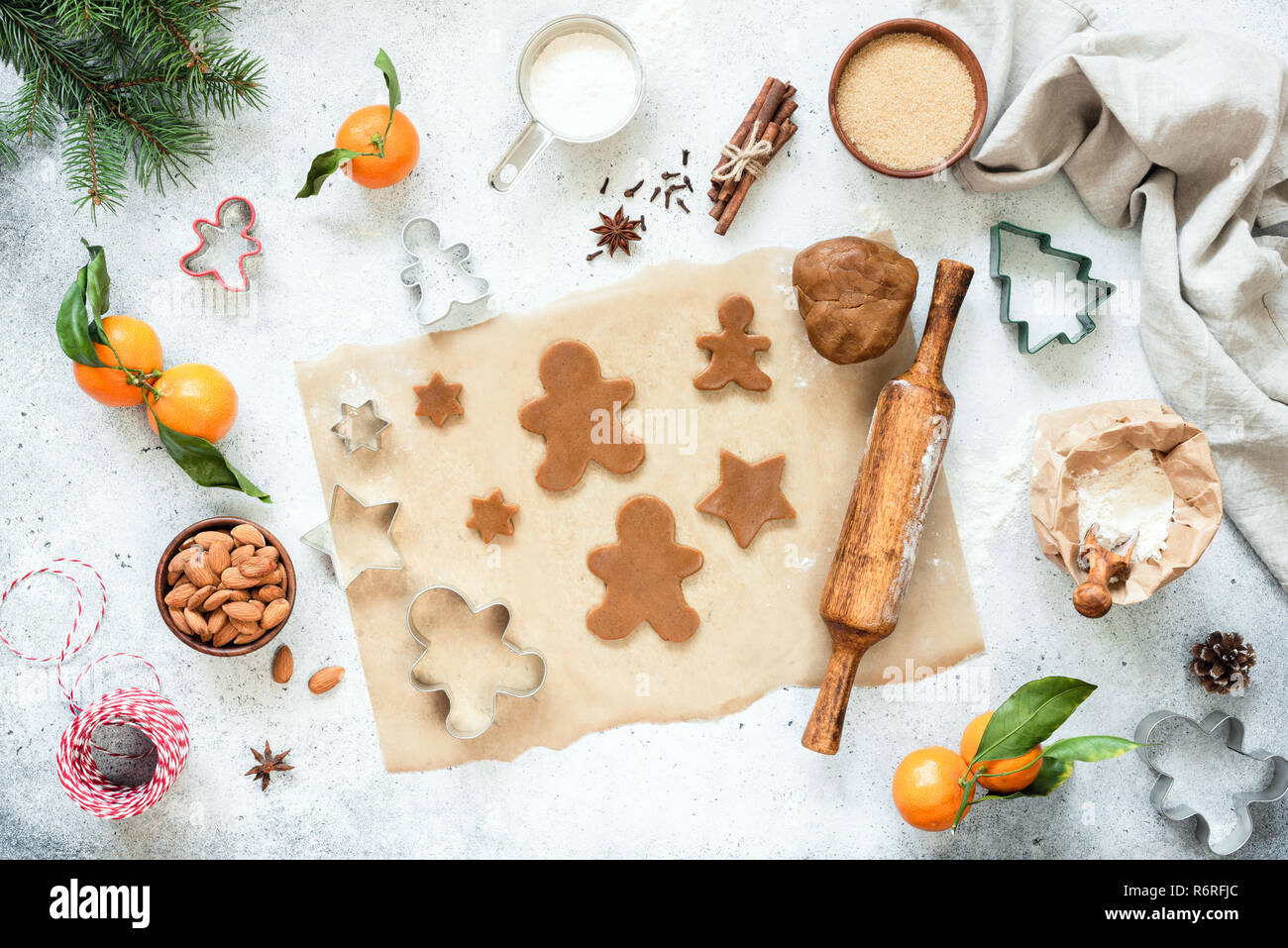 Preparación de las galletas de jengibre. Sin horneado gingerbread cookies y masa de galleta sobre papel pergamino con decoraciones de Navidad. Vista superior, plana Foto de stock