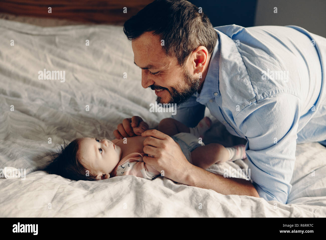 Retrato de mediana edad padre caucásico hablando con bebé recién nacido  hijo hija. Hombre sonriendo de padres a hijos en la cama en el dormitorio  en el hogar. Auténticos li Fotografía de