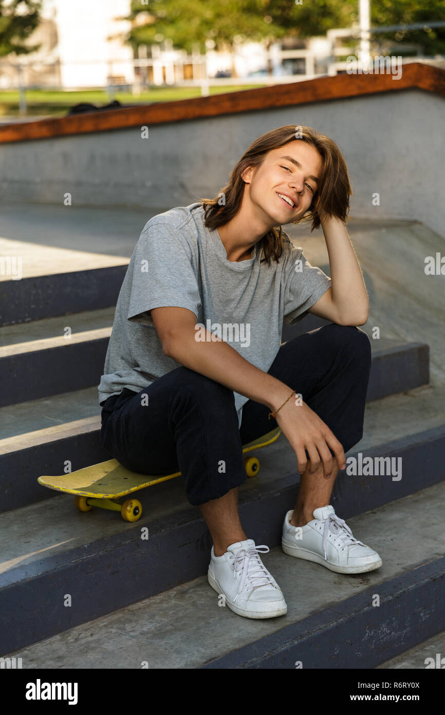 Foto de la hermosa joven skater en ropa casual sentado en en el skate park durante un soleado de verano Fotografía de stock - Alamy