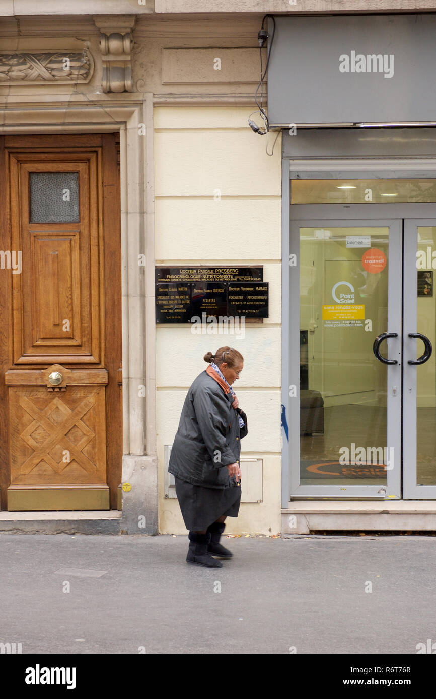 Una mujer caminando por una calle en el 18º arrondissement de París, Francia Foto de stock