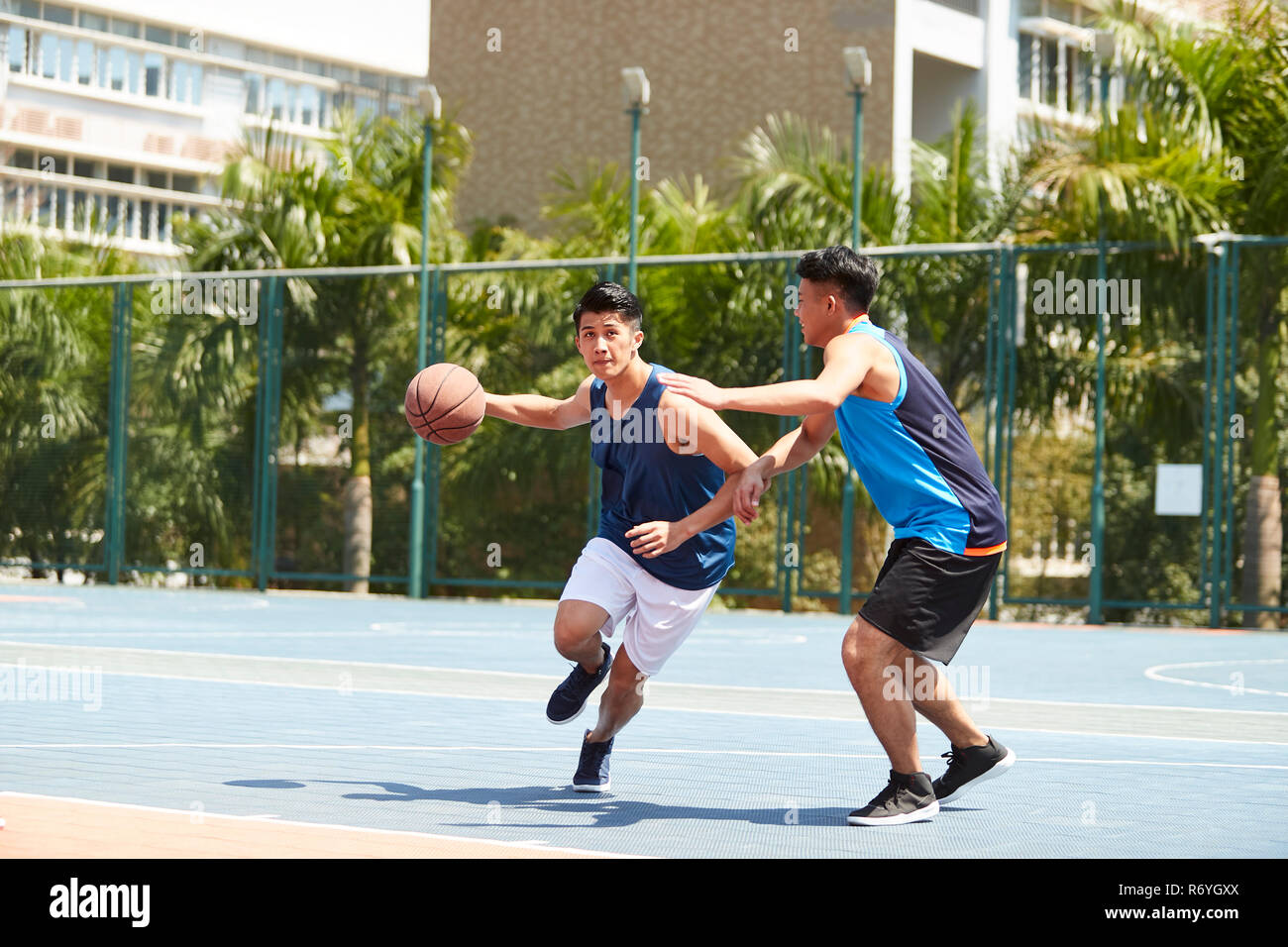 Dos jóvenes jugadores de baloncesto asiático jugando uno contra uno en el tribunal exterior. Foto de stock