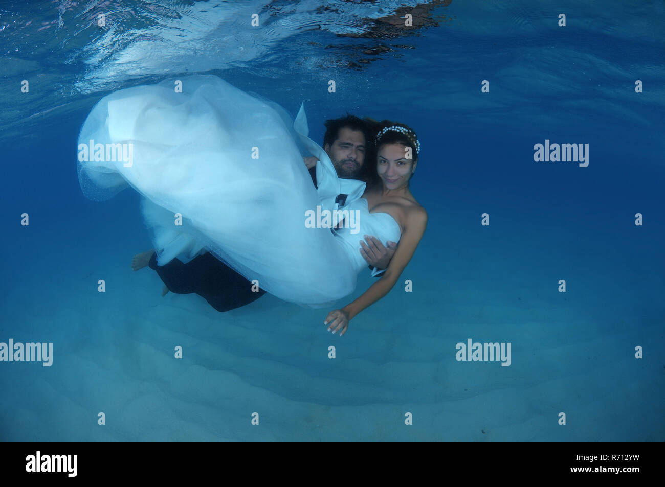 El novio sosteniendo la novia en sus brazos bajo el agua, Océano Índico, Maldivas Foto de stock