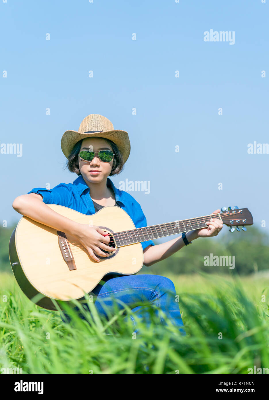 Mujer Pelo Corto Lleve Puesto Un Sombrero Y Gafas De Sol Sentada Tocando La Guitarra En El Campo De Hierba Fotografia De Stock Alamy