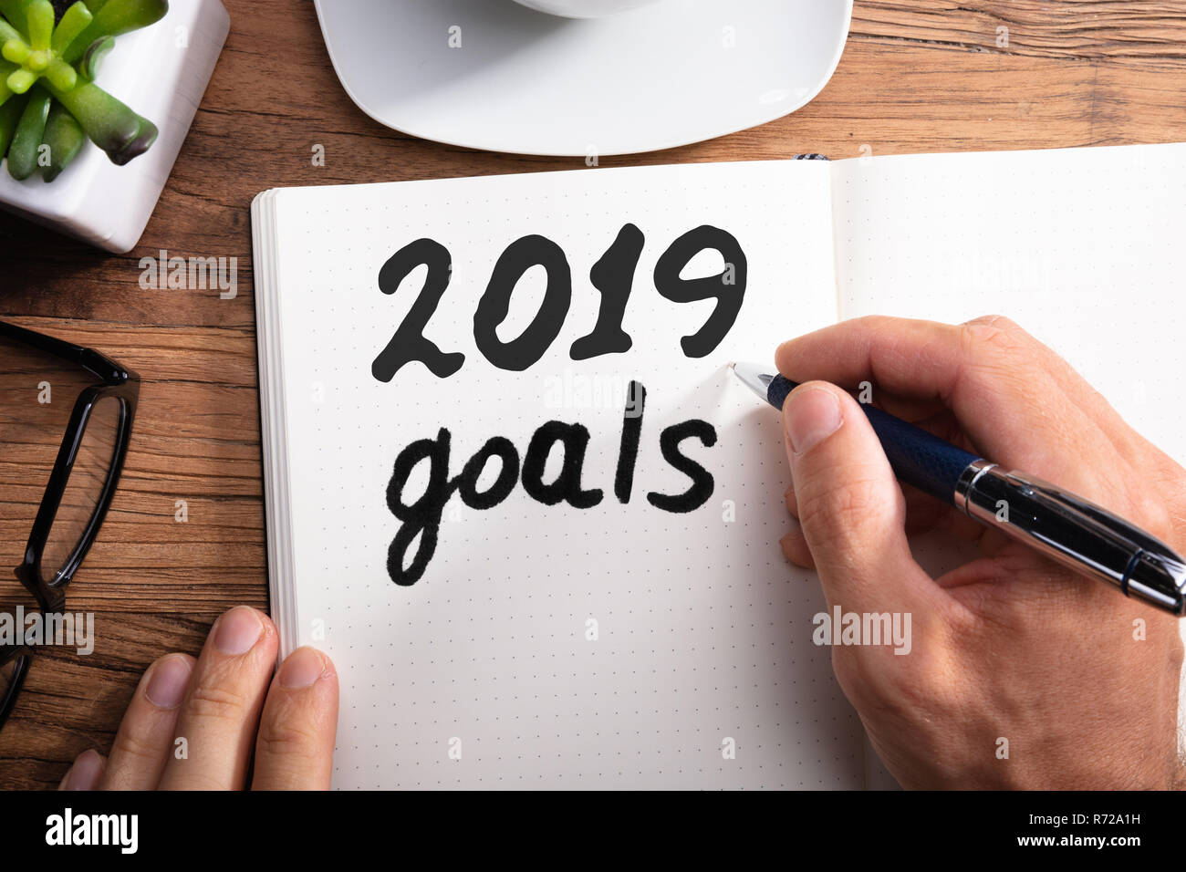 Close-up de la mano de una persona escribir 2019 Año objetivos de puntos portátil de escritorio de madera Foto de stock