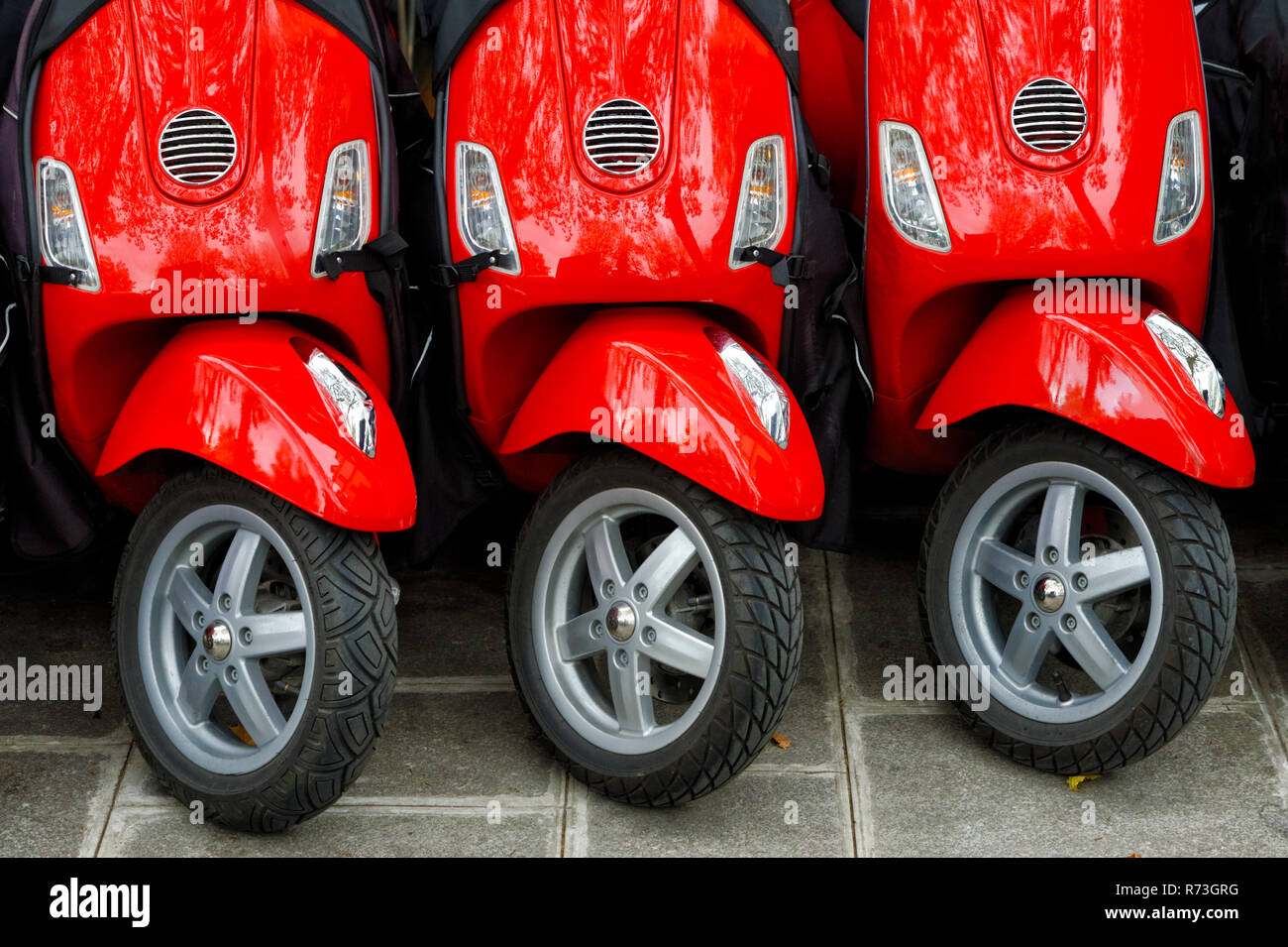 Grupo de tres motos rojas, dispuestas en fila, aparcado al aire libre Foto de stock