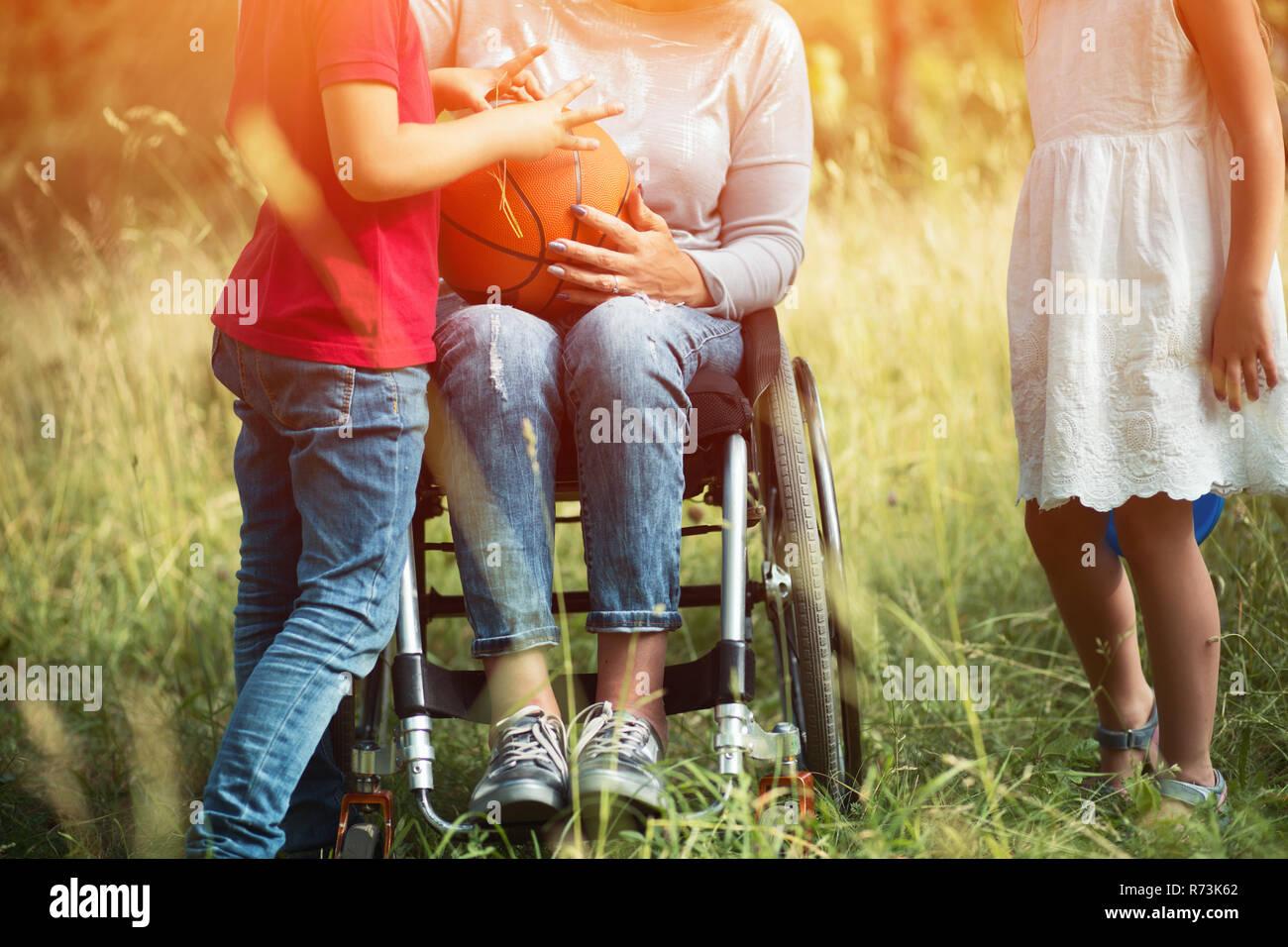 Las piernas de una mujer joven en silla de ruedas con niños aroud su Foto de stock