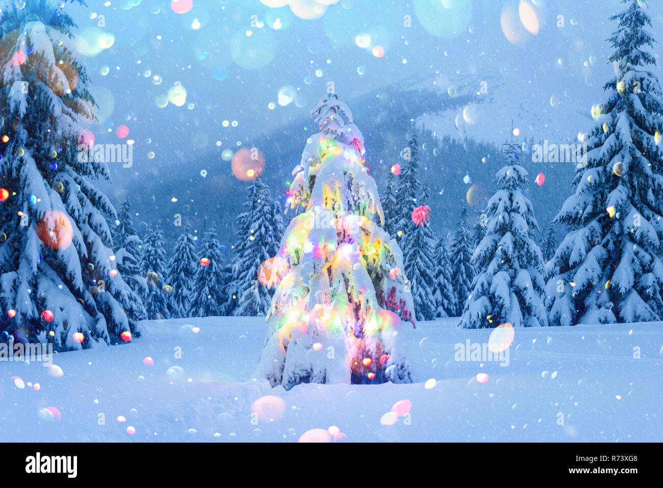 Holiday paisaje con árbol de Navidad, la nieve y las luces en montañas en invierno. Celebración del Año Nuevo postal collage. DOF bokeh luz efecto de postproceso Foto de stock