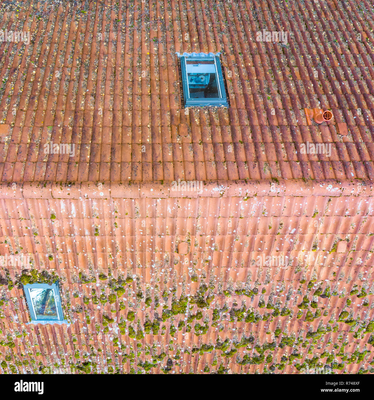 Inspección del techo de tejas rojas de una vivienda unifamiliar, inspección del estado de las tejas en el techo de una casa. Foto de stock