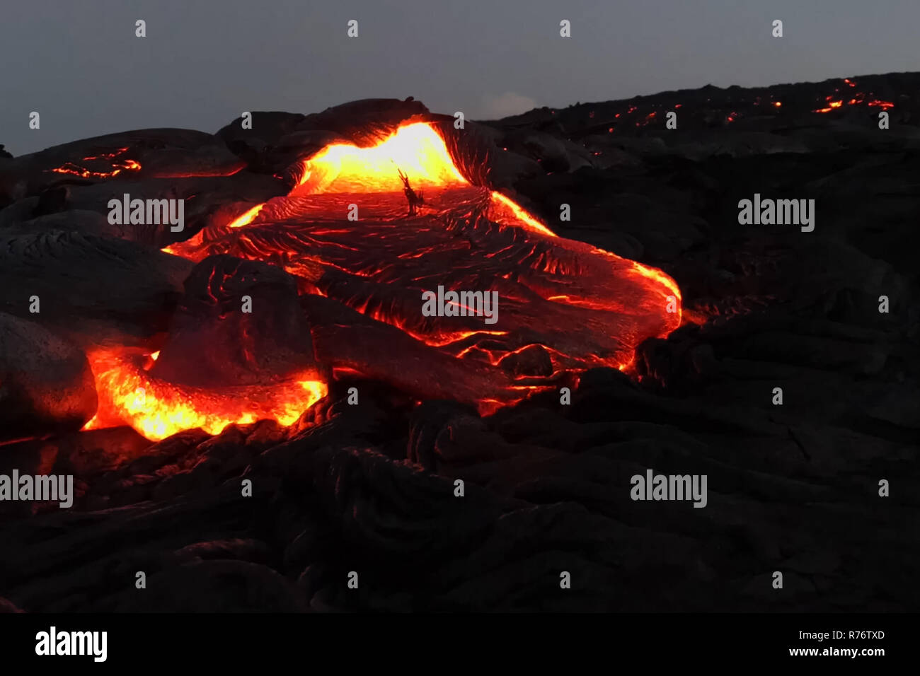 Verter lava en la ladera del volcán. Erupción volcánica y magma. Foto de stock