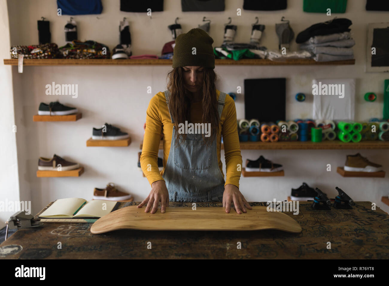 Mujer examinar skateboard deck en el taller Foto de stock