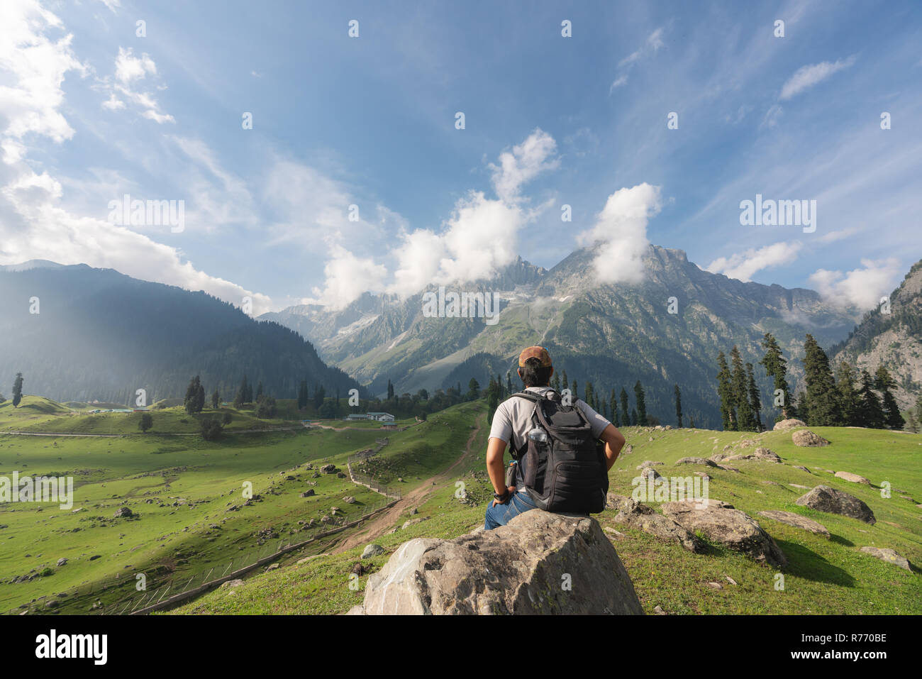 Hombre viajero con mochila relajarte y disfrutar de la hermosa vista del paisaje de montaña y naturaleza en verano. Viajes y vacaciones de verano en el estilo de vida Foto de stock